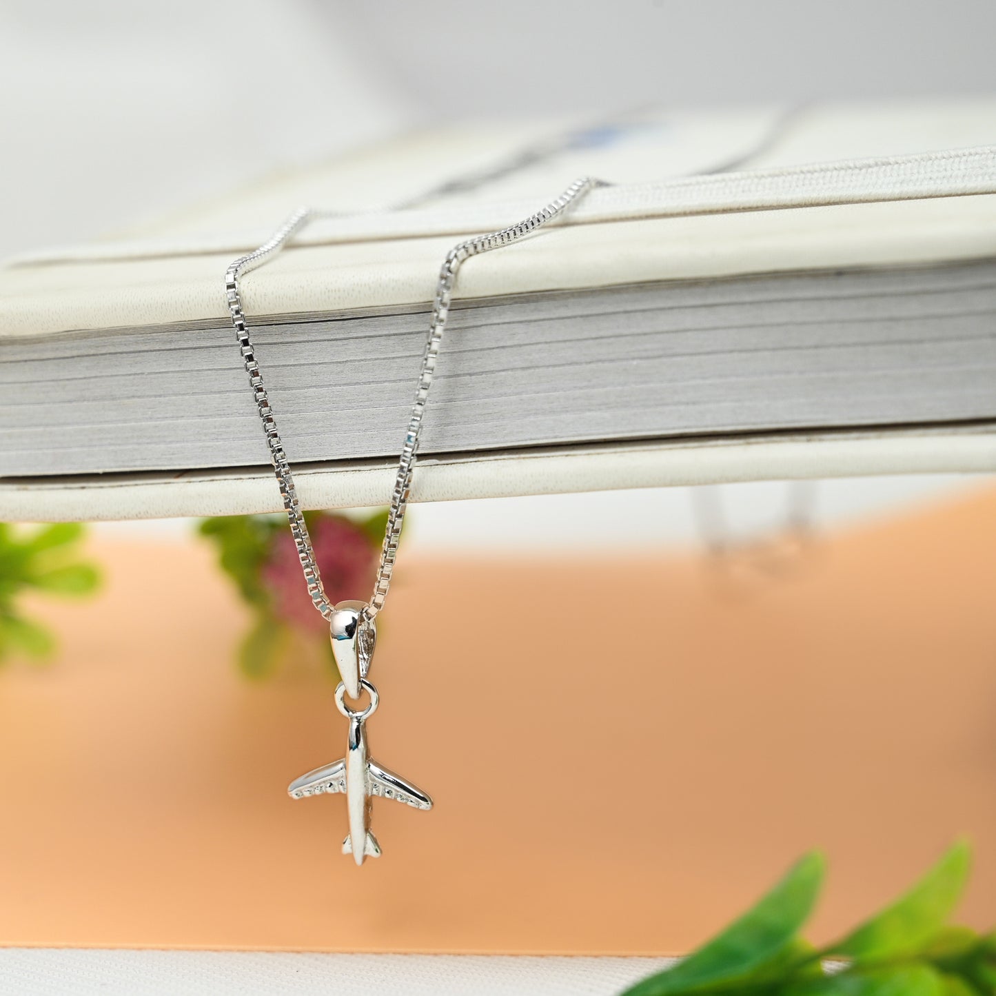 Aeroplane shaped silver pendant with chain beautifully displayed