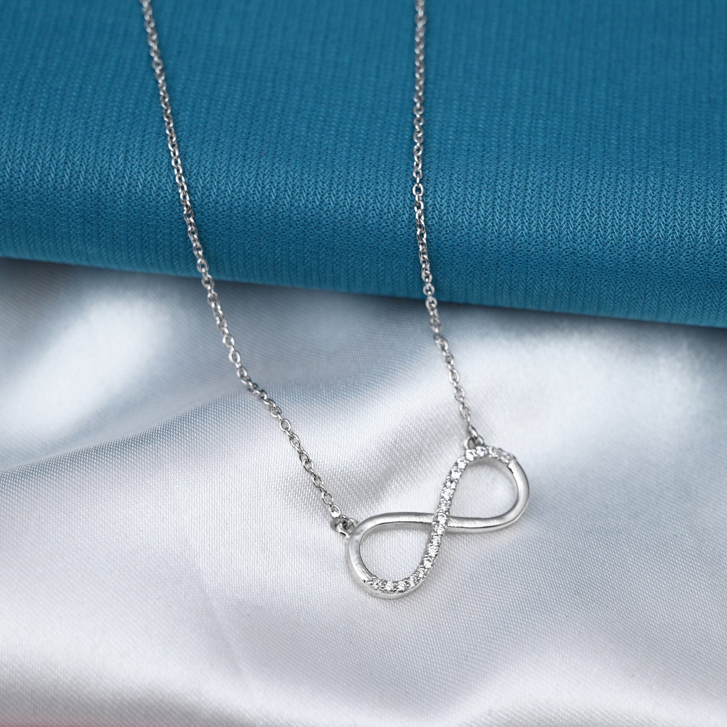 Infinity pendant on a silver chain secured by a fish-shaped lock.