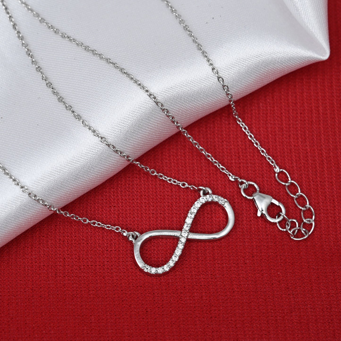 Infinity symbol pendant on silver chain with fish-shaped lock.