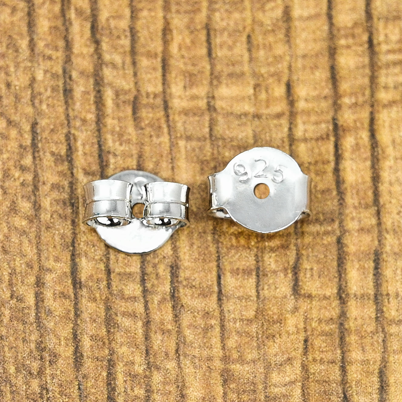 Shiny silver earring push backs designed to hold stud earrings in place.